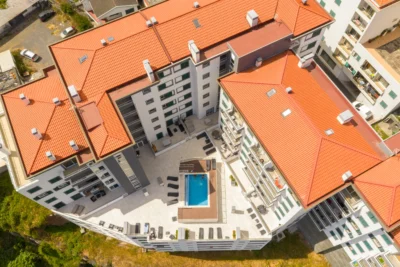 Widok z góry na taras z basenem i leżakami, kompleks w Caniço.