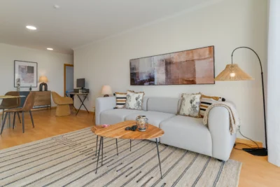 Salon z wygodną sofą, biurkiem i jadalnią — wyjście na balkon.