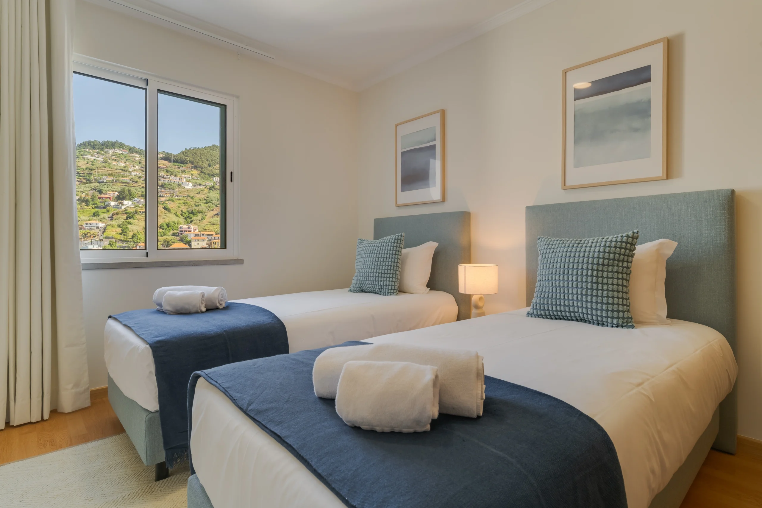 Sypialnia z dwoma łóżkami pojedynczymi i widokiem na zielone wzgórza.