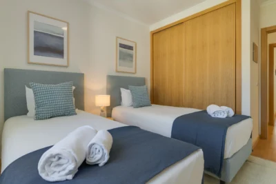 Sypialnia z dwoma łóżkami i dużą szafą przesuwną, jasne wnętrze.