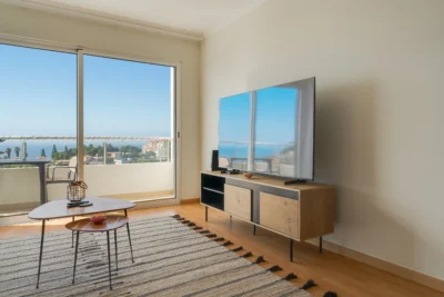 Strefa TV przy przesuwnych drzwiach balkonowych z widokiem na ocean.