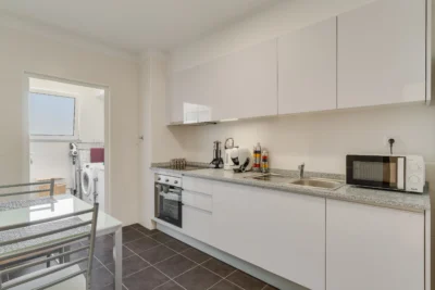 Jasna kuchnia w pełni wyposażona; przejście do pralni z pralką i oknem.