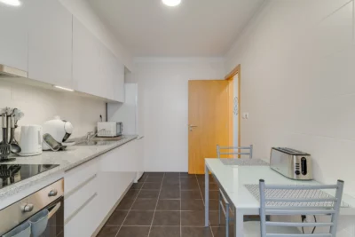 Kuchnia z blatem roboczym, stołem jadalnianym i małym AGD, minimalistyczna.