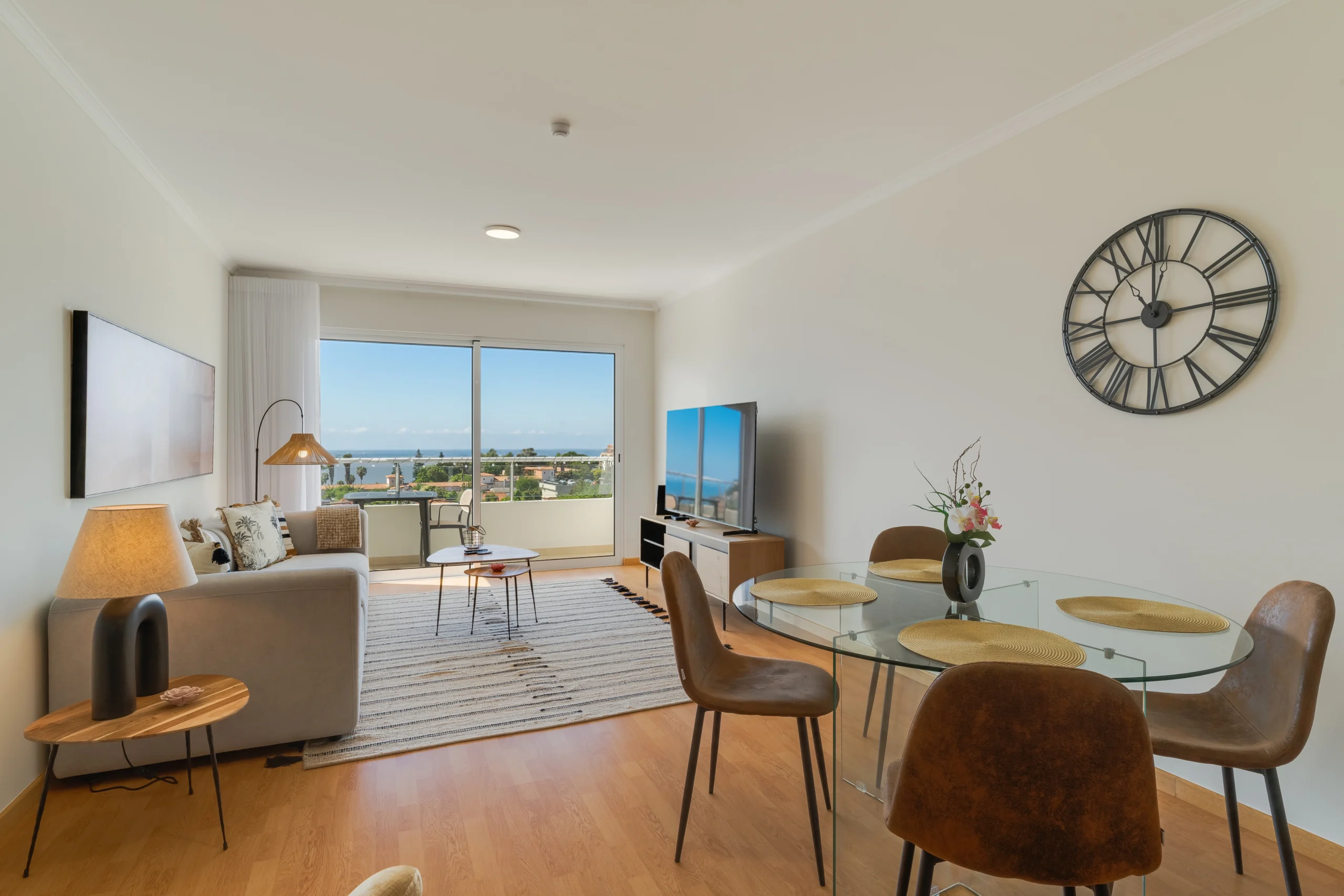 Panoramiczny widok salonu i jadalni na ocean przez szerokie okna.