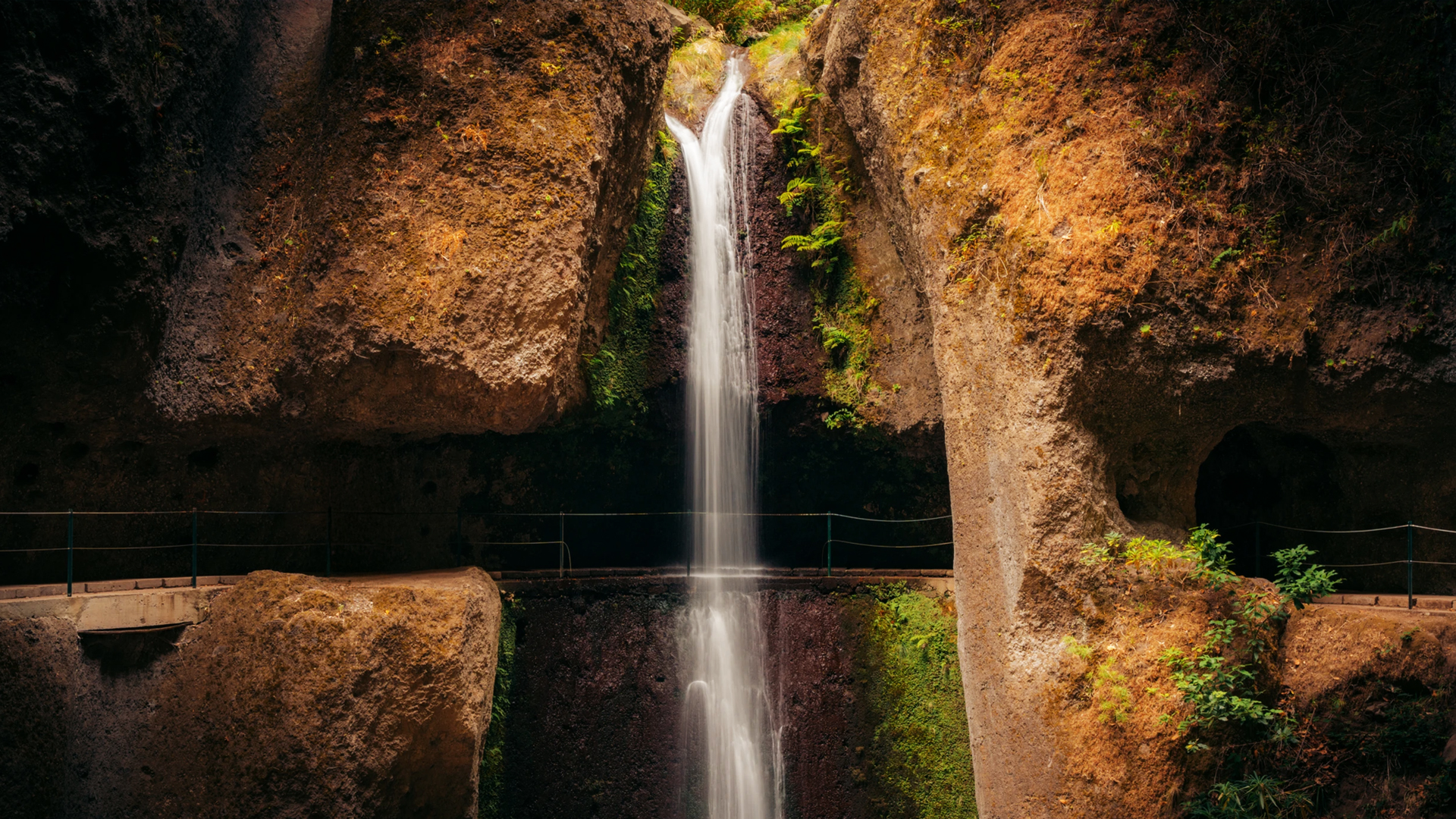 Wąski szlak lewady na klifie i wodospad, za którym przechodzi się na Levada Nova w Ponta do Sol.
