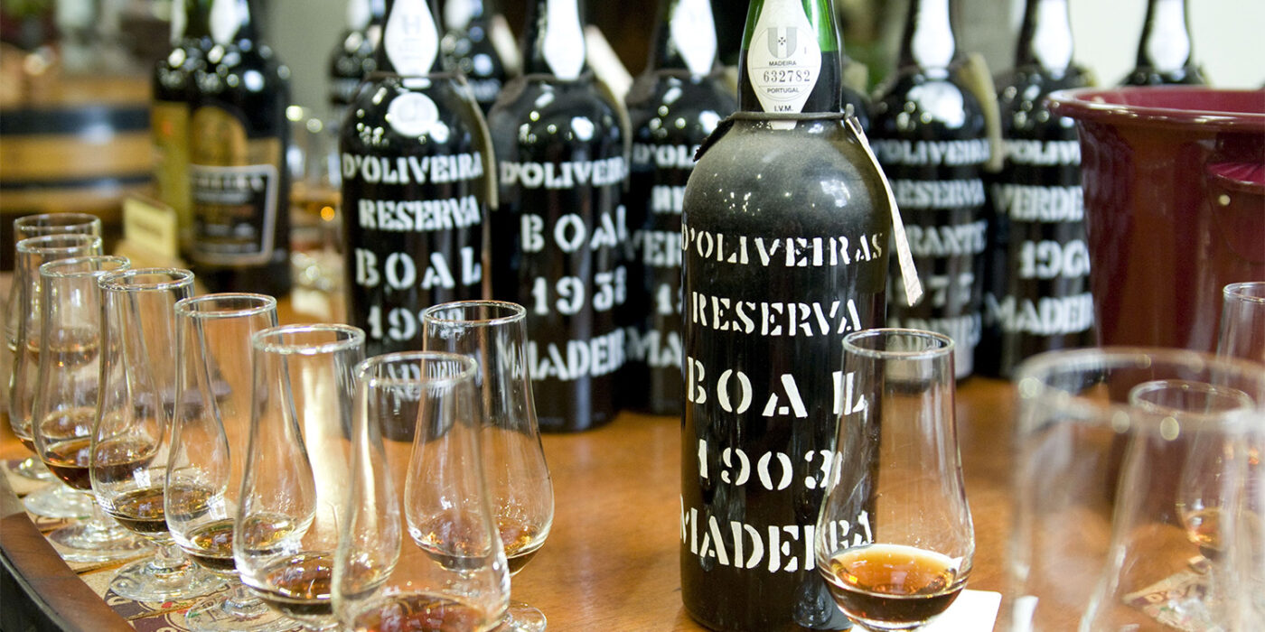 Butelki wina Madera i kieliszki ustawione na ladzie podczas degustacji.