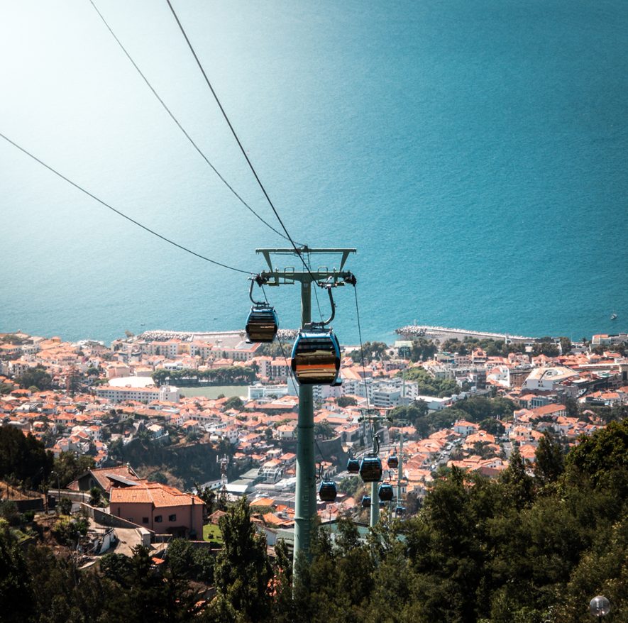 Panorama Funchal widziana z kolejki linowej, z dachami miasta i oceanem w tle.
